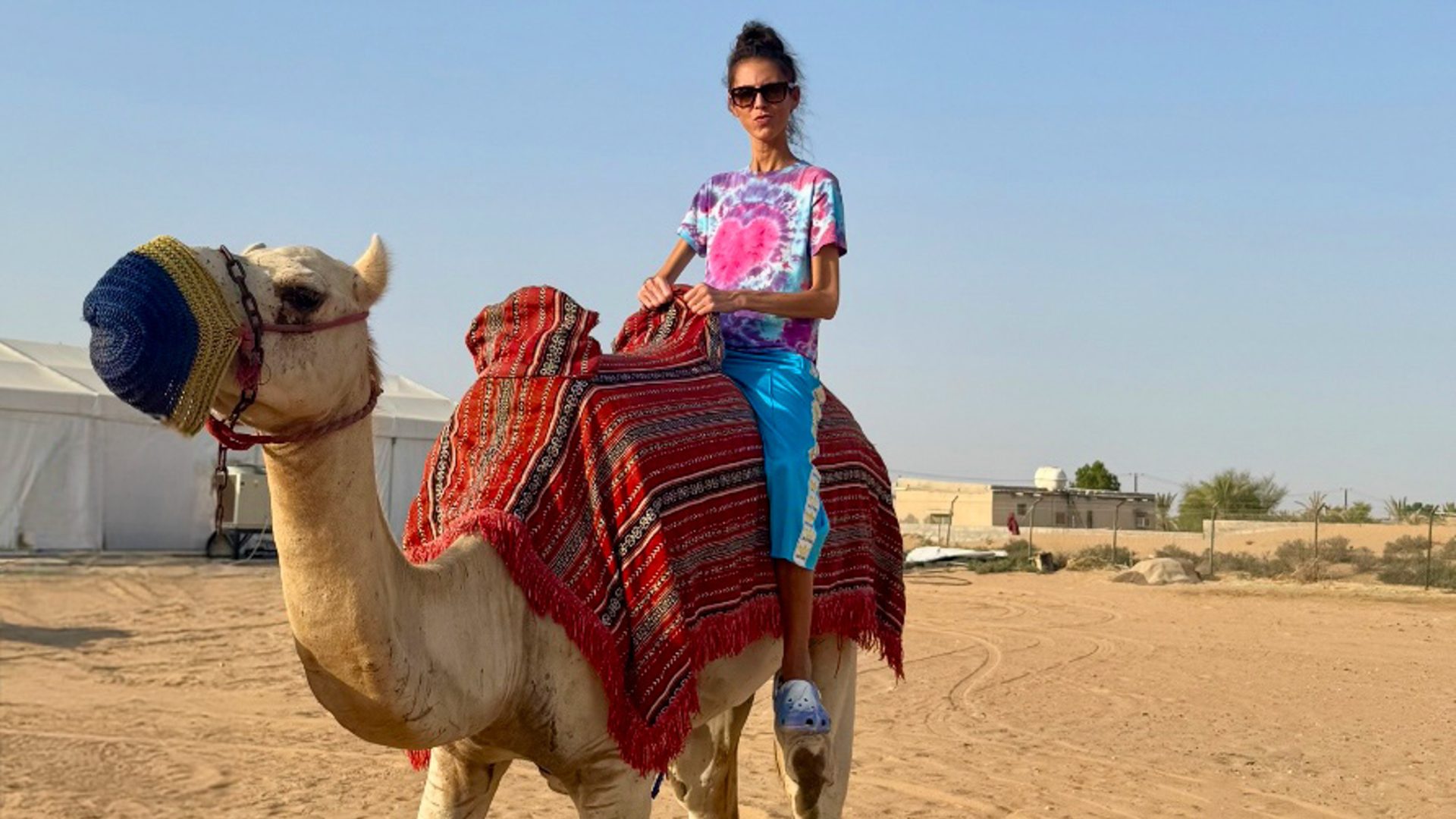 A woman on a camel in a desert setting.