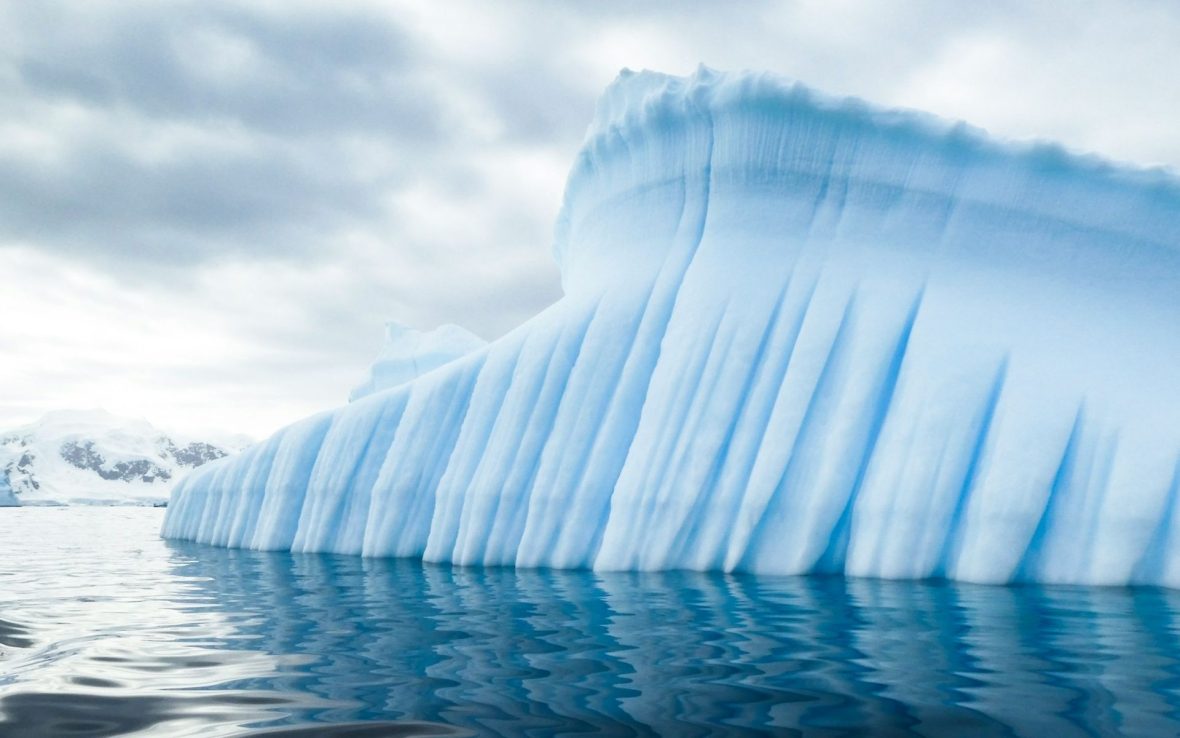 A close-up of a large iceberg, with wind-battered lines running vertically along its side.