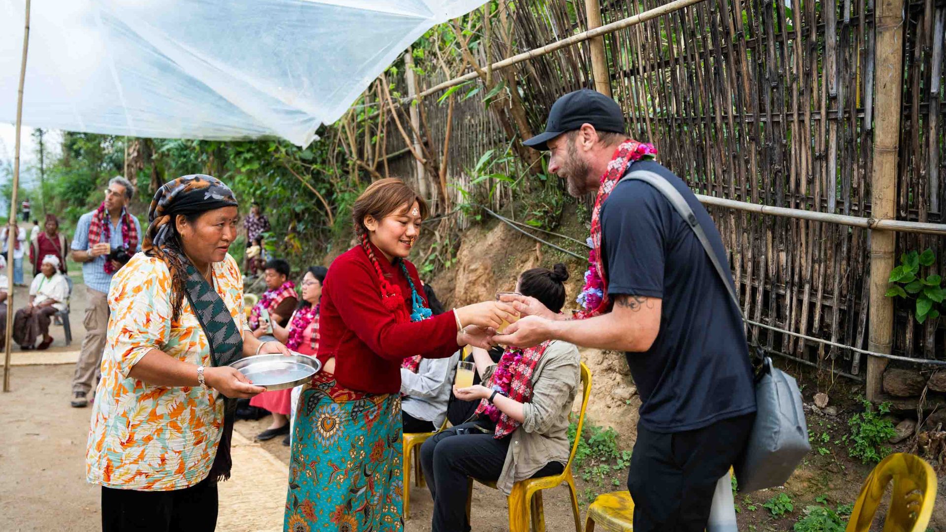 A Nepalese woman offers a tourist a cup of juice.