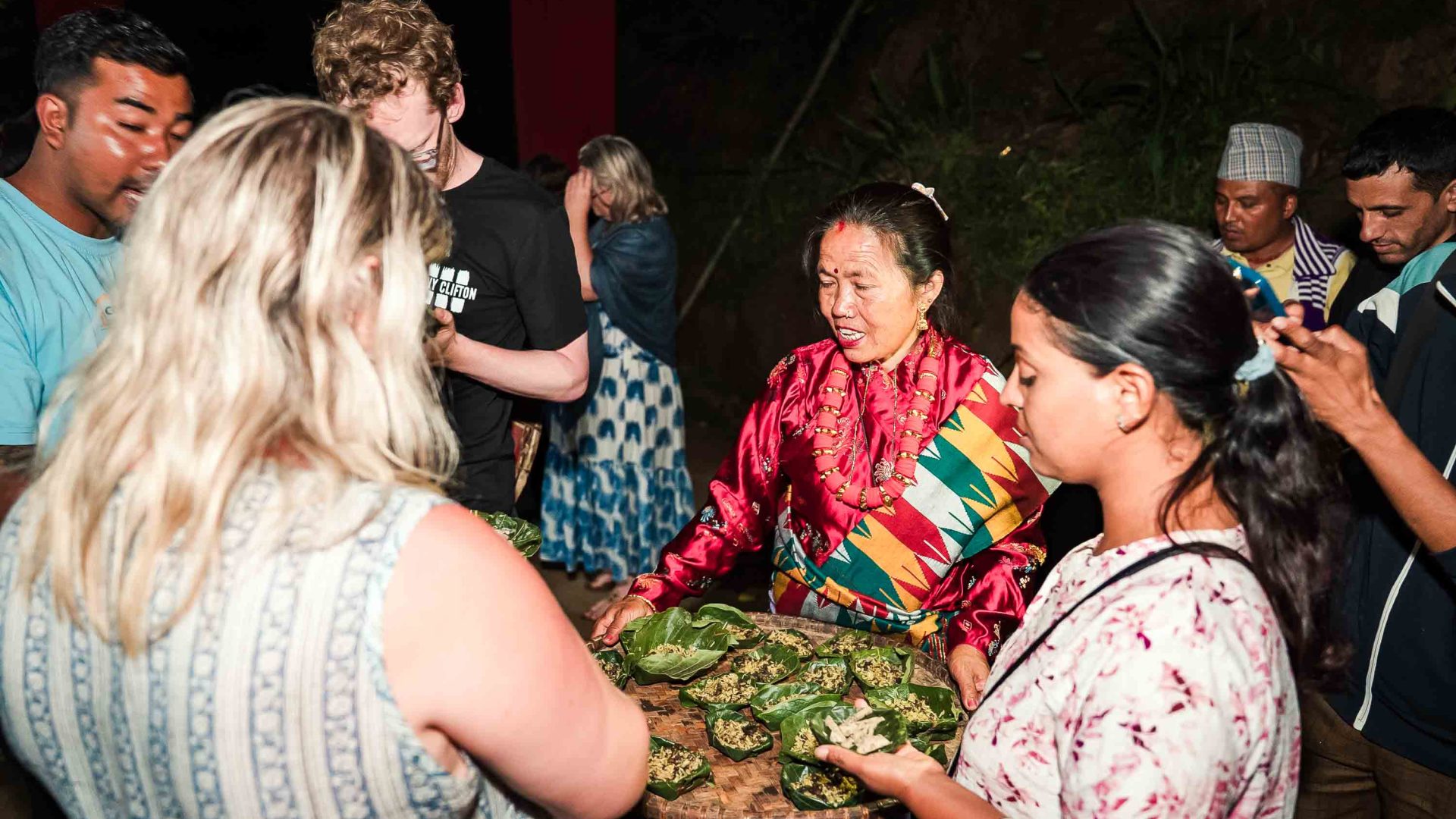 A woman holds out a tray of offerings to tourists.