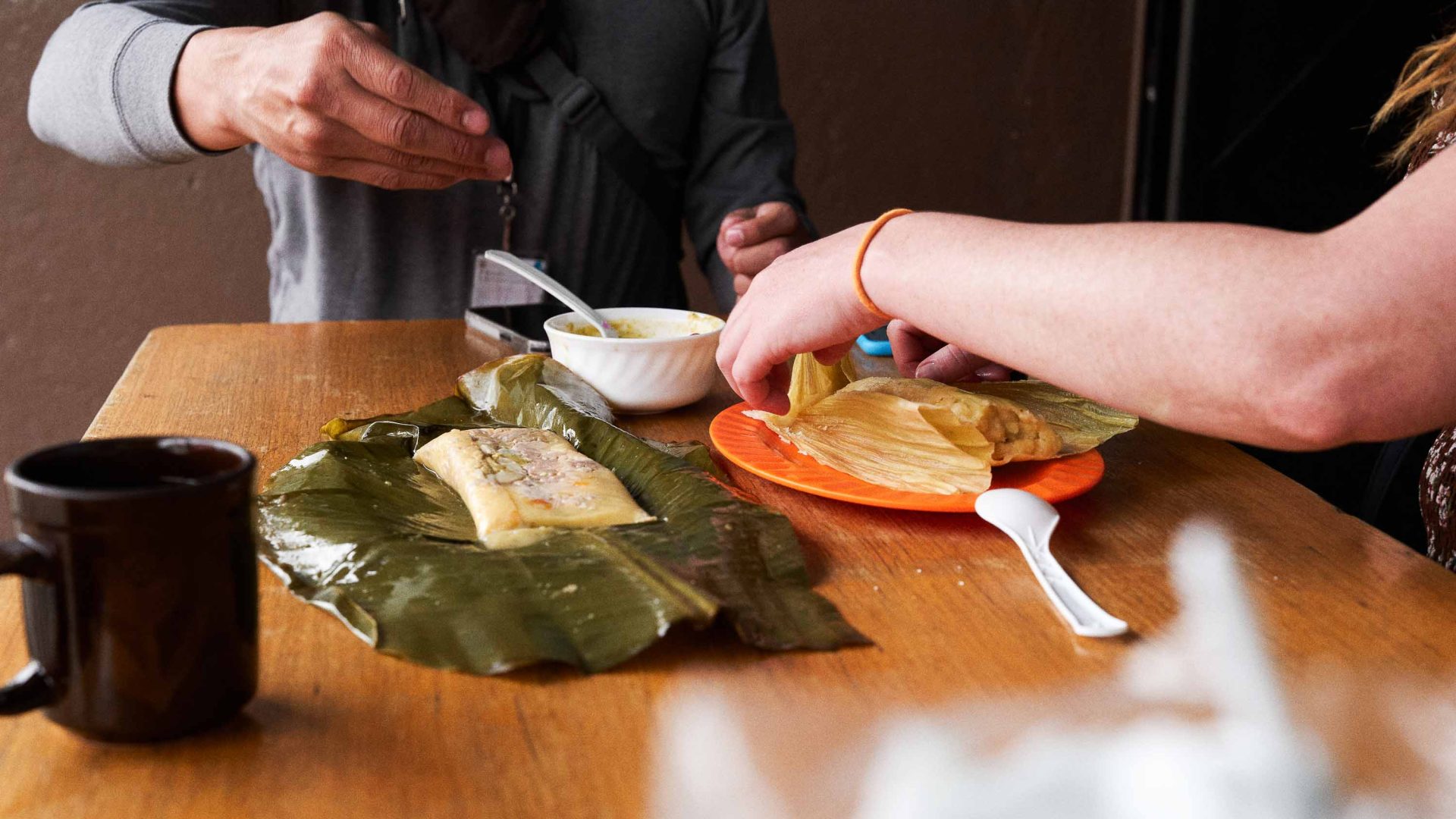Two people share a meal wrapped in a banana leaf.