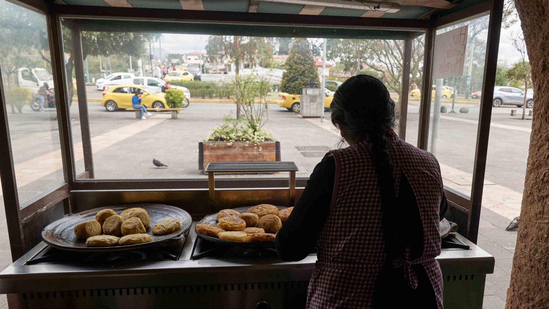 A woman prepares food over a stove set up outside.