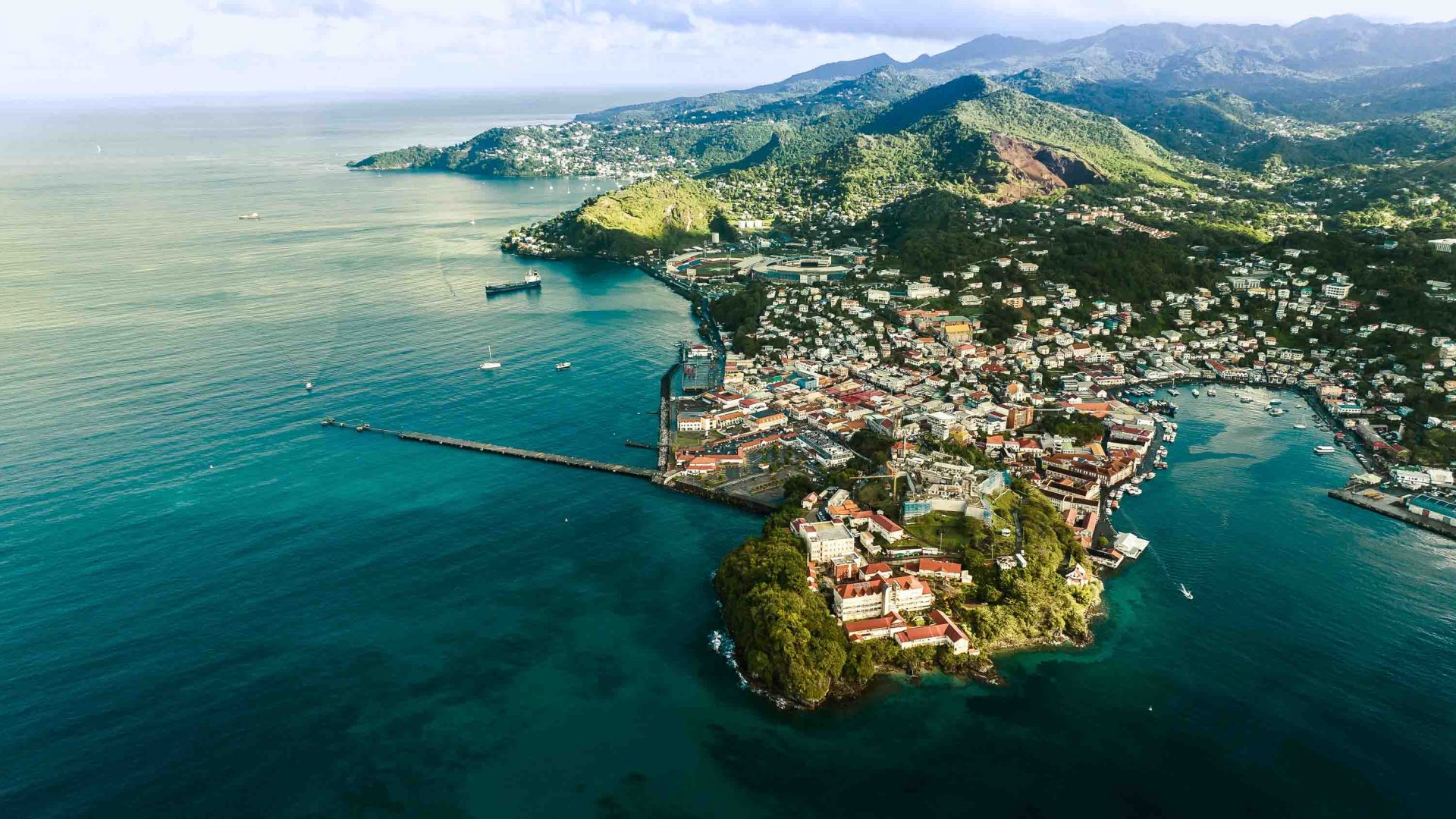 Hills lead down to a city. It is all surrounded by the sea.