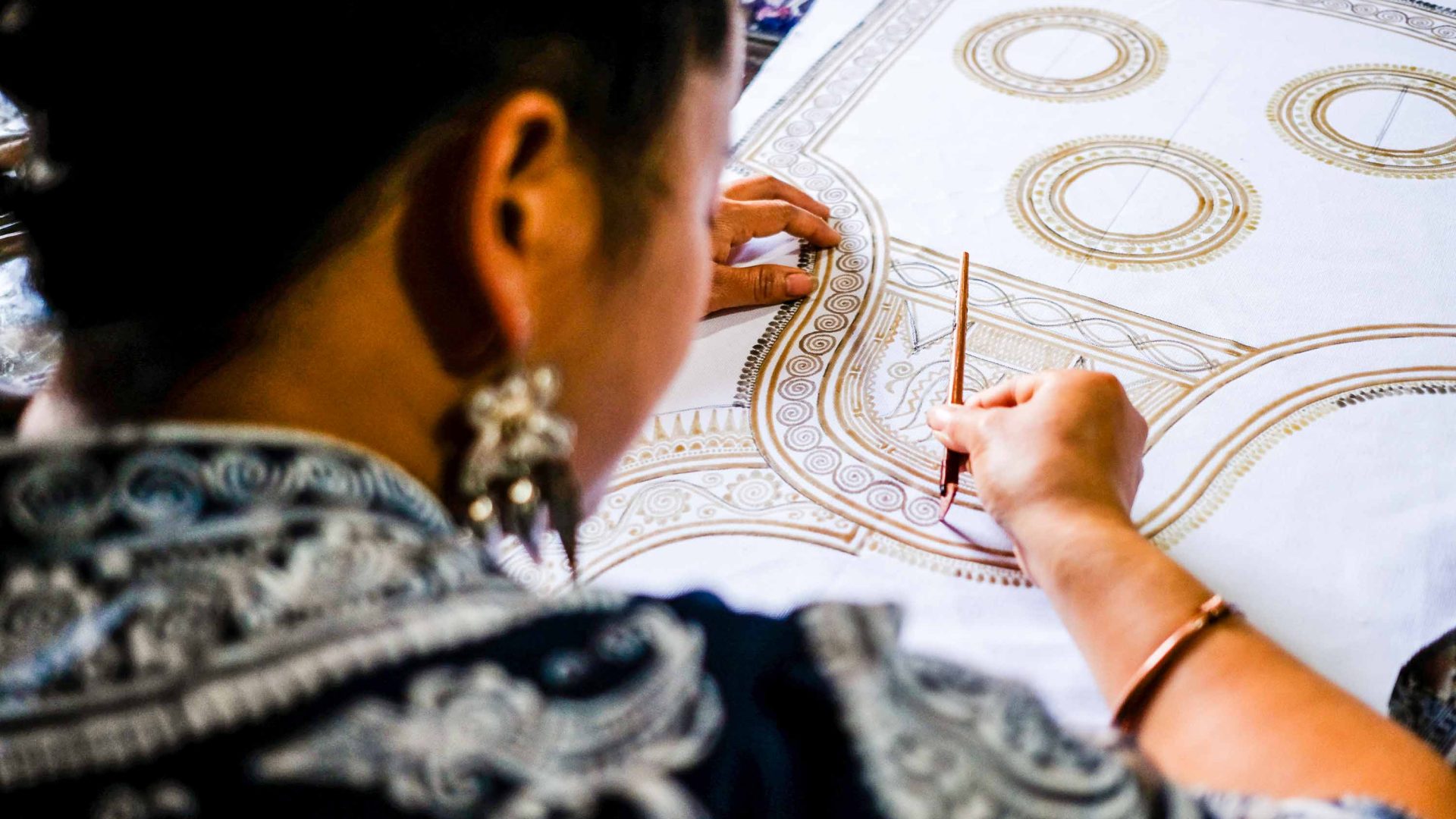 A woman does designs on fabric.