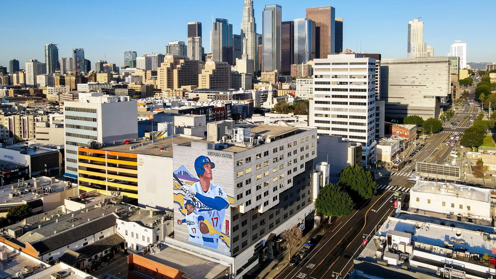 A mural of a man with a baseball bat at the entry to a plaza.