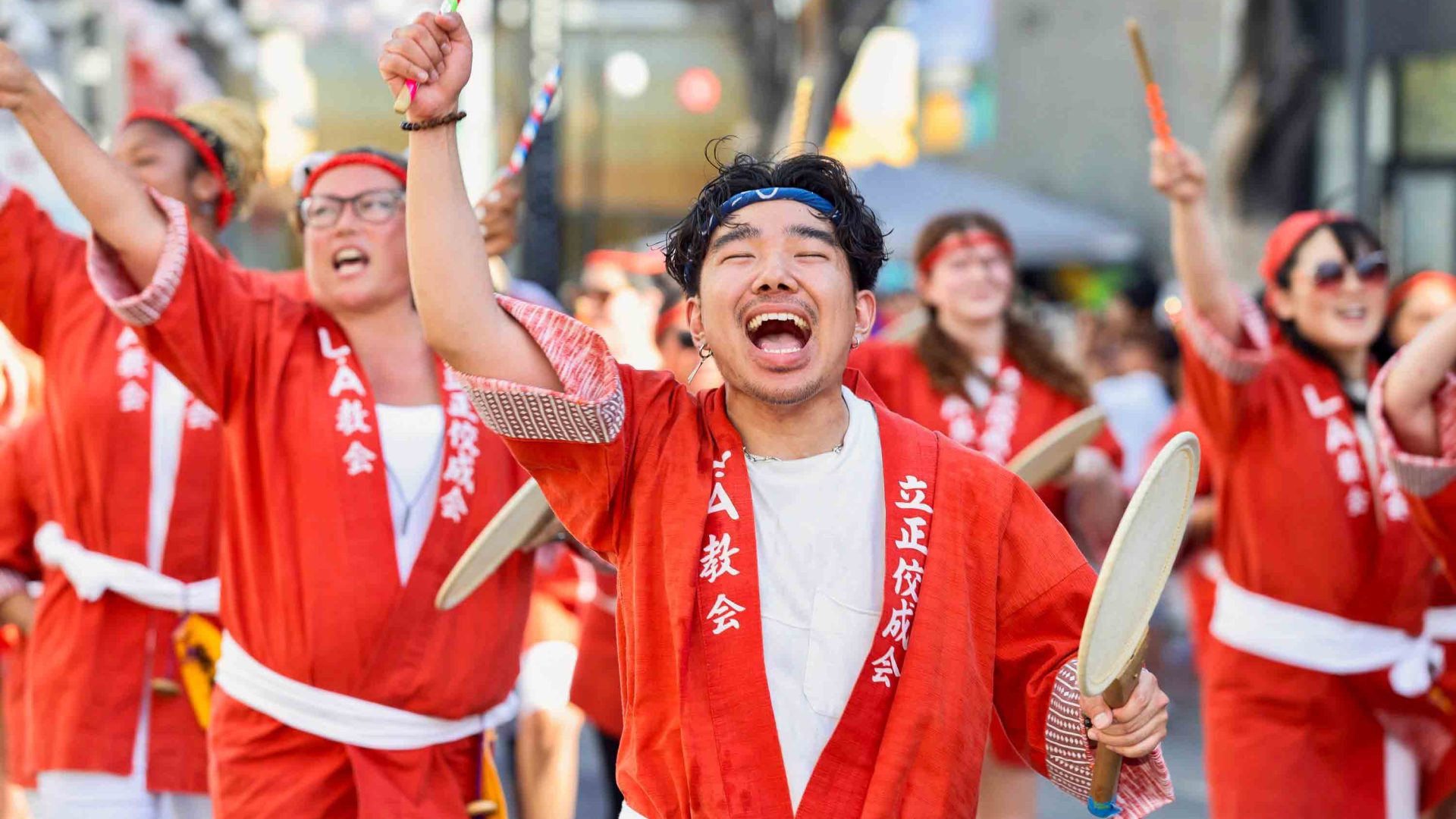 People in red traditional clothing dance and celebrate in a parade.