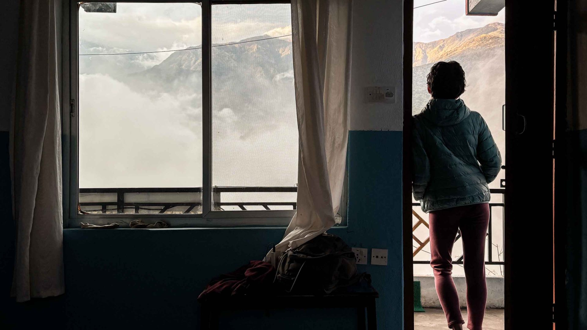 A person looks out the door of a teahouse towards mountains.
