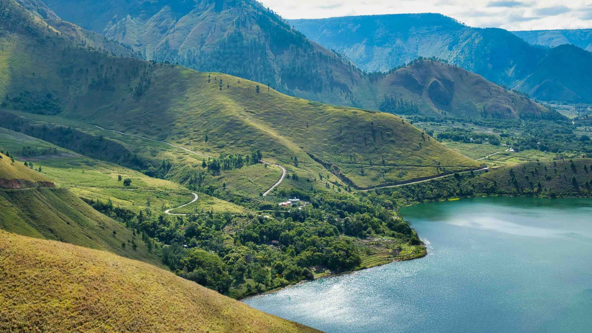 Green hills drop down to a lake.