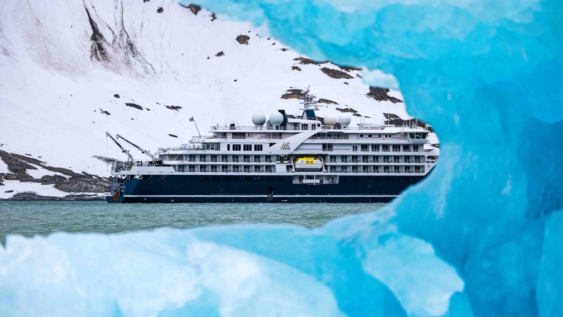 A cruise ship seen through a hole in an iceberg.