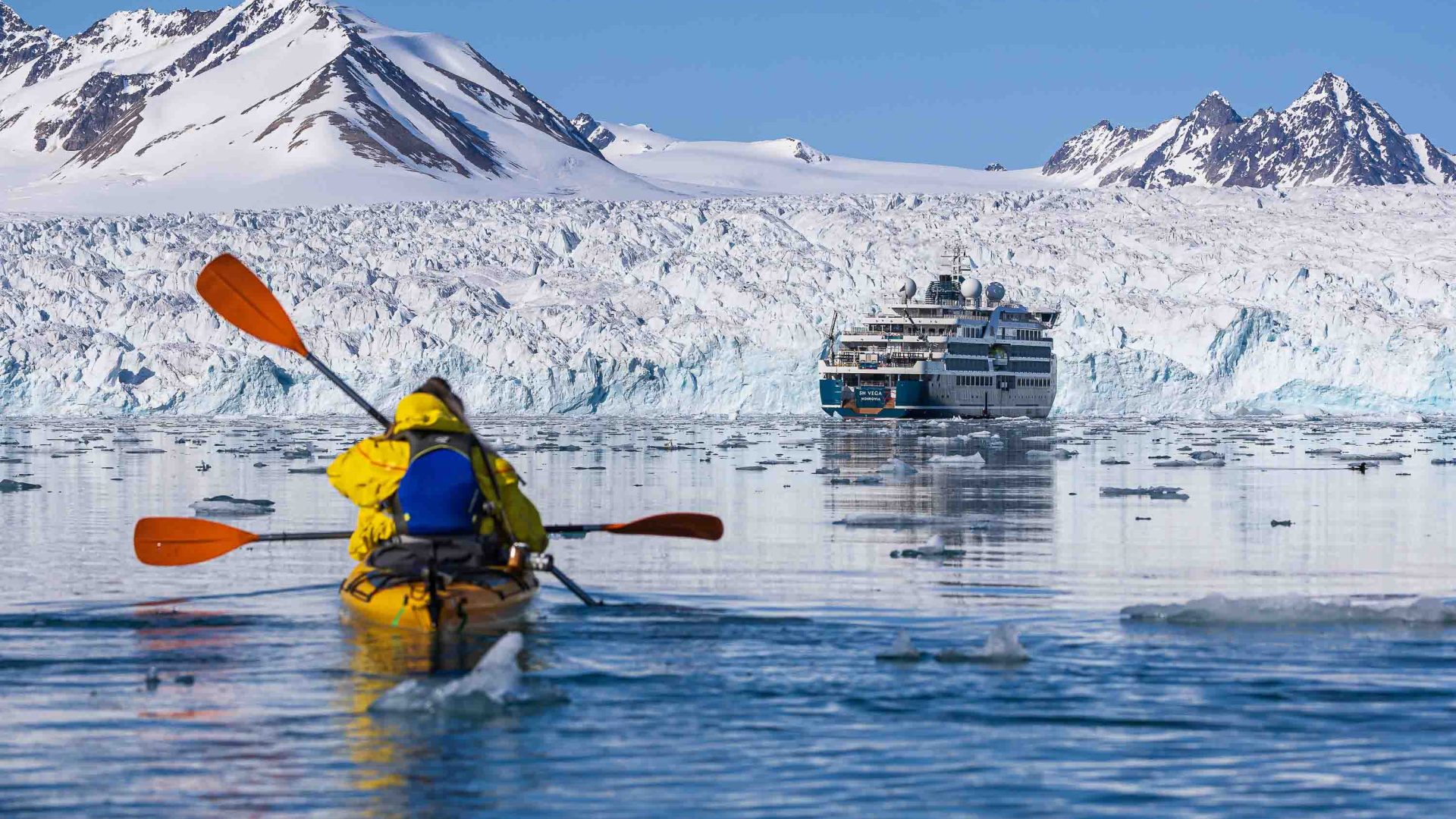 A person kayaks in the direction of the cruise ship and also a glacier.