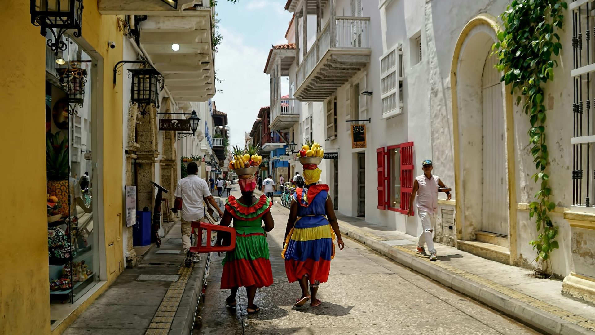 Two women dressed colorfully walk white and yellow painted street