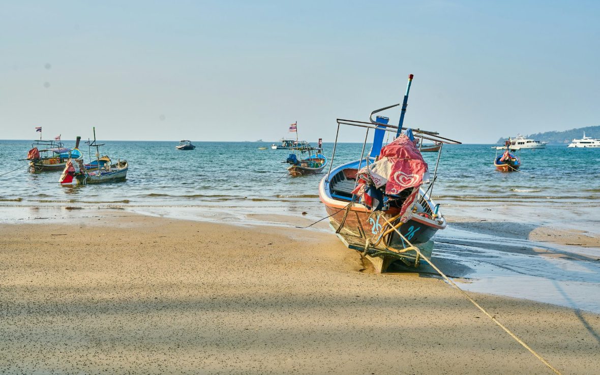 Colorful boats anchored to white sand shoreline