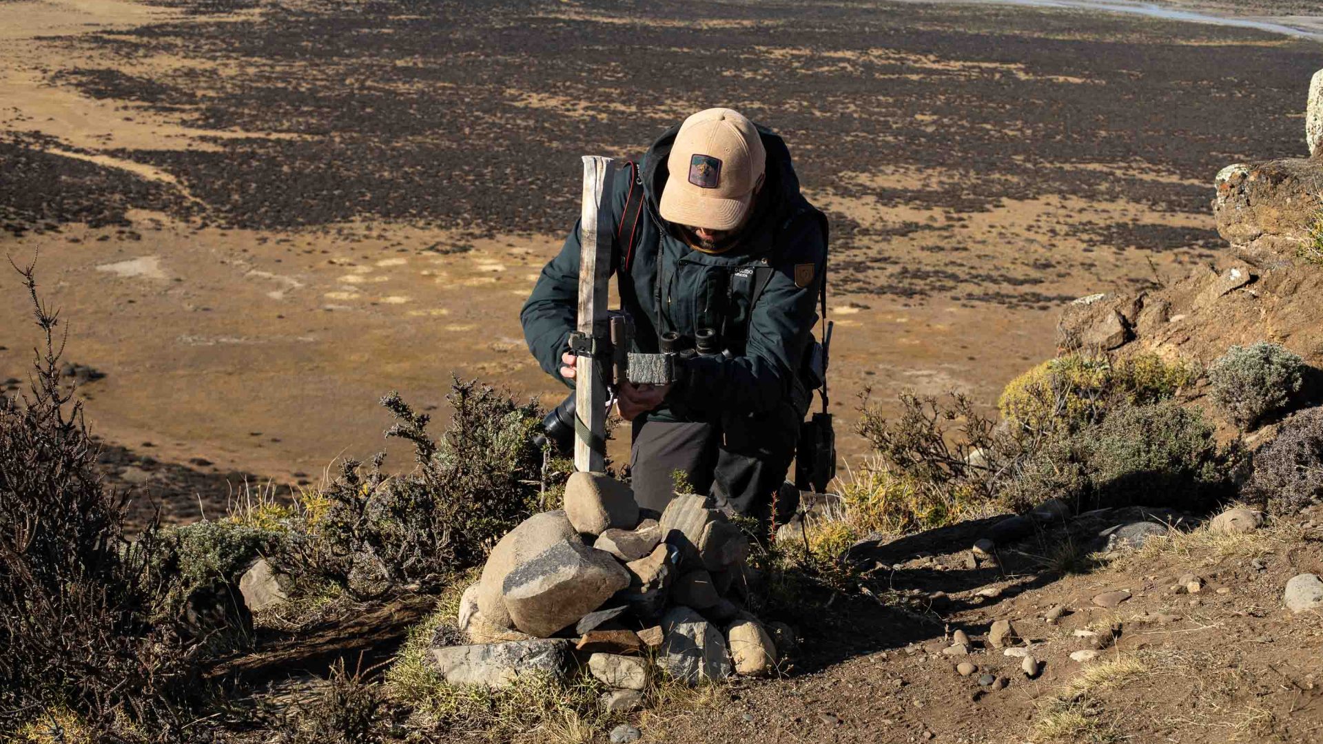 A man bends down to check on a camera trap.
